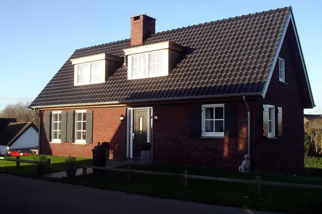 Nieuwbouwwoning van donkere baksteen met dakkapellen in Ammerzoden