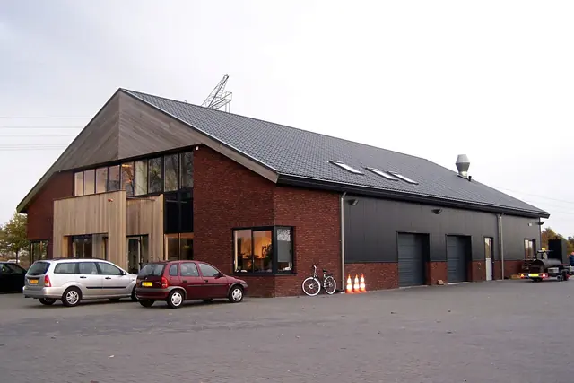 Nieuwbouw van een bedrijfspand met houten gevelbekleding en rode baksteen in Berlicum