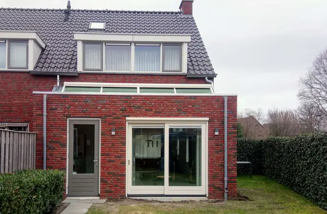 Aanbouw van rode baksteen met schuifpui aan de achterzijde van een woning in Den Dungen